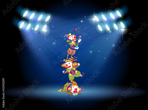 Three clowns performing on the stage with spotlights