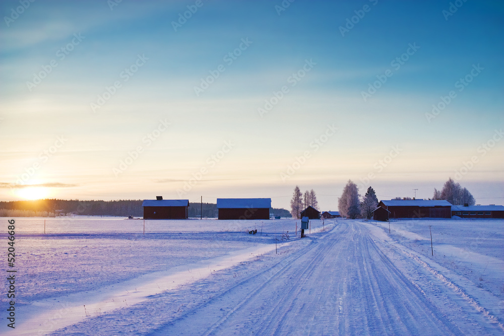 Snow covered road at winter evening with sunset