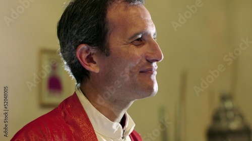 Young catholic priest on altar in church, talking and smiling