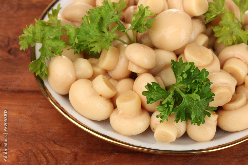 Marinated mushrooms in saucer on wooden table Marinated mushrooms in saucer on wooden table