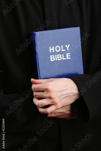 Priest holding holy bible, close up