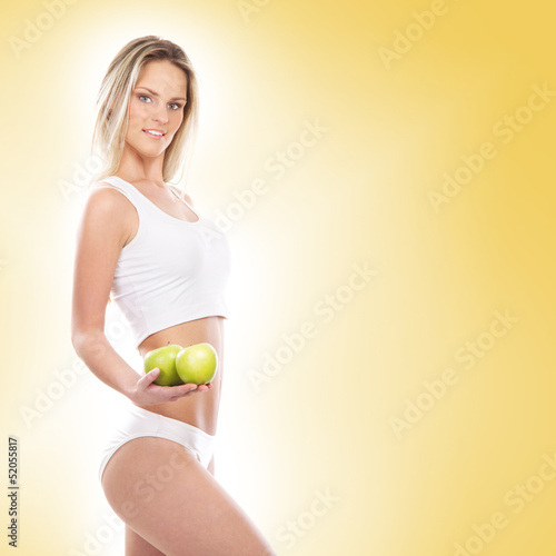 A young sexy woman in sporty clothes holding apples