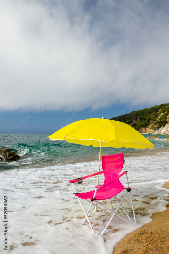 Yellow parasol and pink chair at the beach
