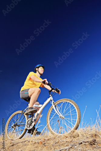 A young male wearing yellow shirt and helmet on a bike
