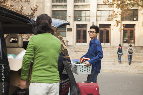 Young man moving into dormitory on college campus photo