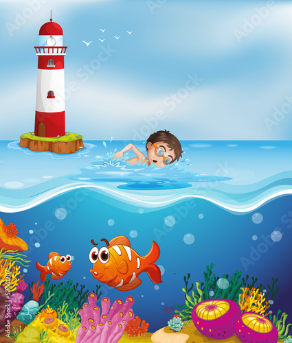 A boy swimming at the beach with a lighthouse