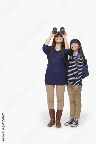 Mother looking through binoculars with daughter next to her © xixinxing