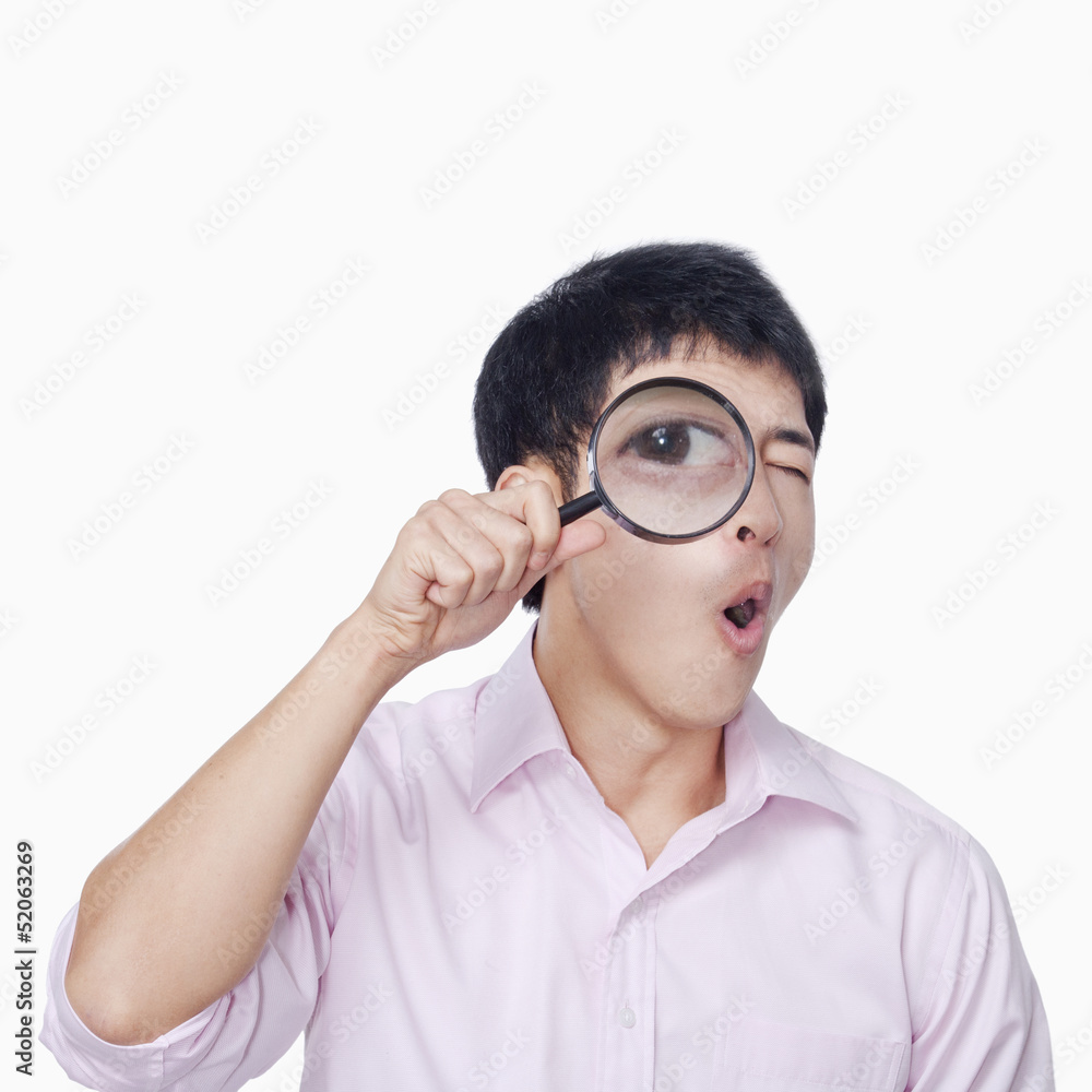Young man looking through magnifying glass Young man looking through magnifying glass