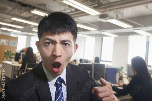 Young Businessman pointing and shouting, looking at camera