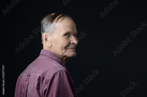 senior looking over his shoulder on black background