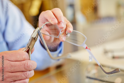 Fototapeta Naklejka Na Ścianę i Meble -  Hand of optician fixing glasses
