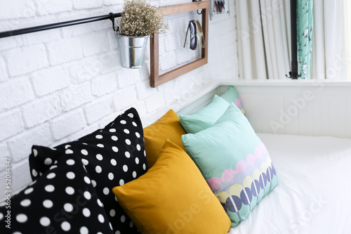 Colorful pillows on a sofa with white brick wall in background