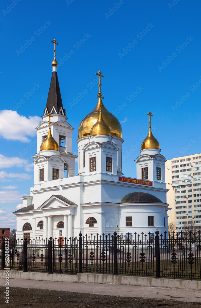 White cathedral with golden domes of the forged fence on a sunny