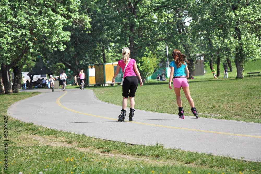 Two girls go on roller skates on a beautiful sunny day Two girls go on roller skates on a beautiful sunny day