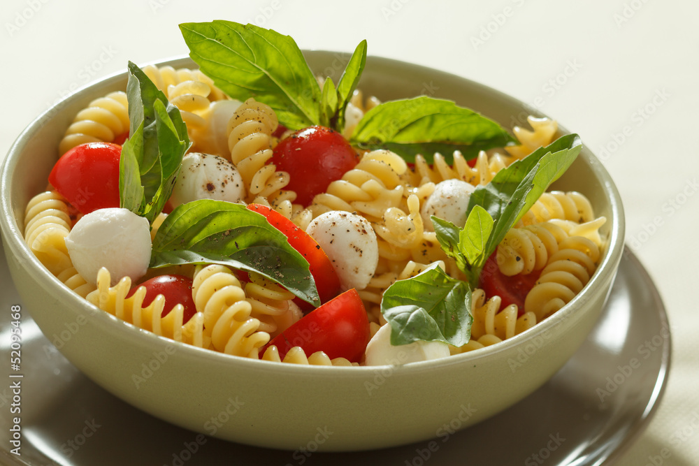 Pasta salad with cherry tomatoes, basil leaves and mozzarella