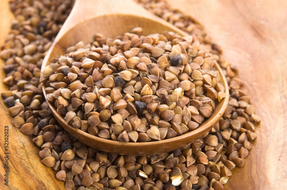 Buckwheat seeds on wooden spoon in closeup Buckwheat seeds on wooden spoon in closeup