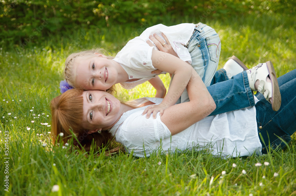 A young girl with mather on a green grass A young girl with mather on a green grass