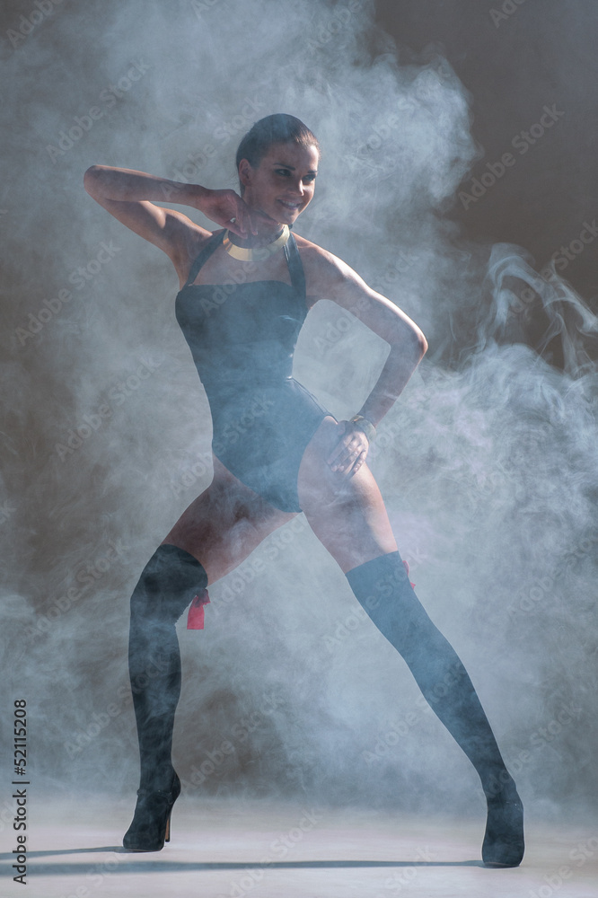 Modern style dancer posing on a studio grey background in fog
