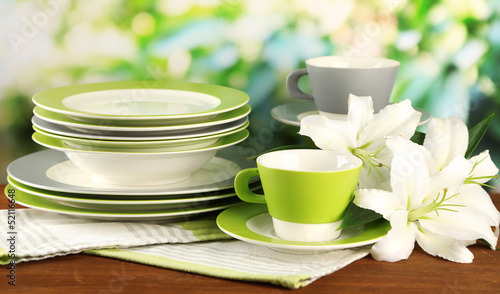 Fototapeta Naklejka Na Ścianę i Meble -  Empty plates and cups on wooden table on green background