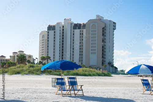 beach with deck chair near to buildings in a sunny morning