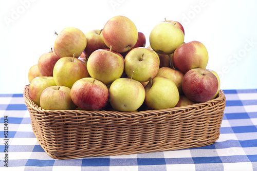 Korb mit Äpfeln auf karierter Tischdecke