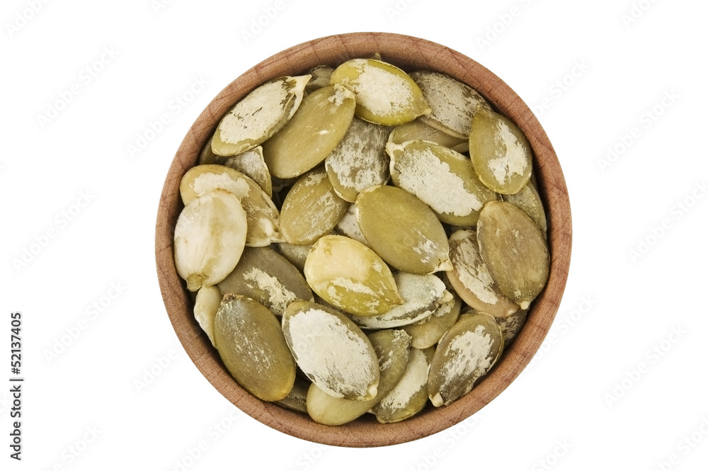 Shelled raw pumpkin seeds in wooden bowl isolated on white Shelled raw pumpkin seeds in wooden bowl isolated on white