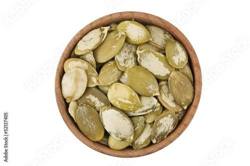 Shelled raw pumpkin seeds in wooden bowl isolated on white