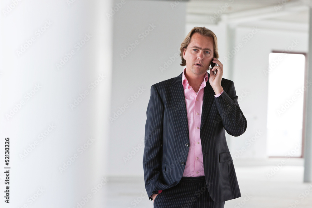 Business man calling with his cellphone in white office. Business man calling with his cellphone in white office.