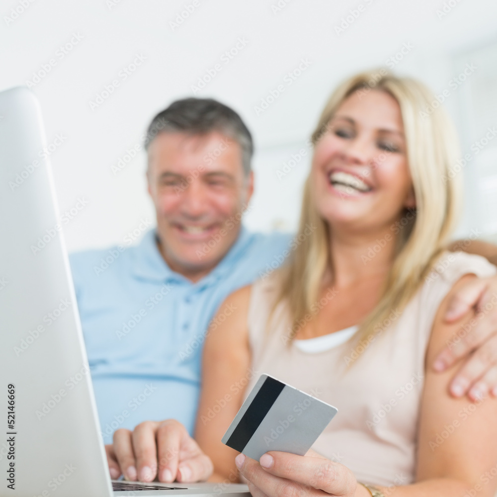 Couple using laptop on the sofa to shop online Couple using laptop on the sofa to shop online