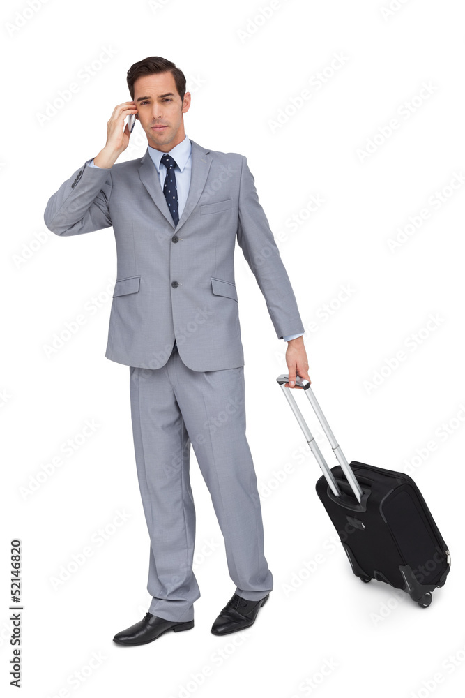 Serious businessman on the phone while holding his suitcase Serious businessman on the phone while holding his suitcase