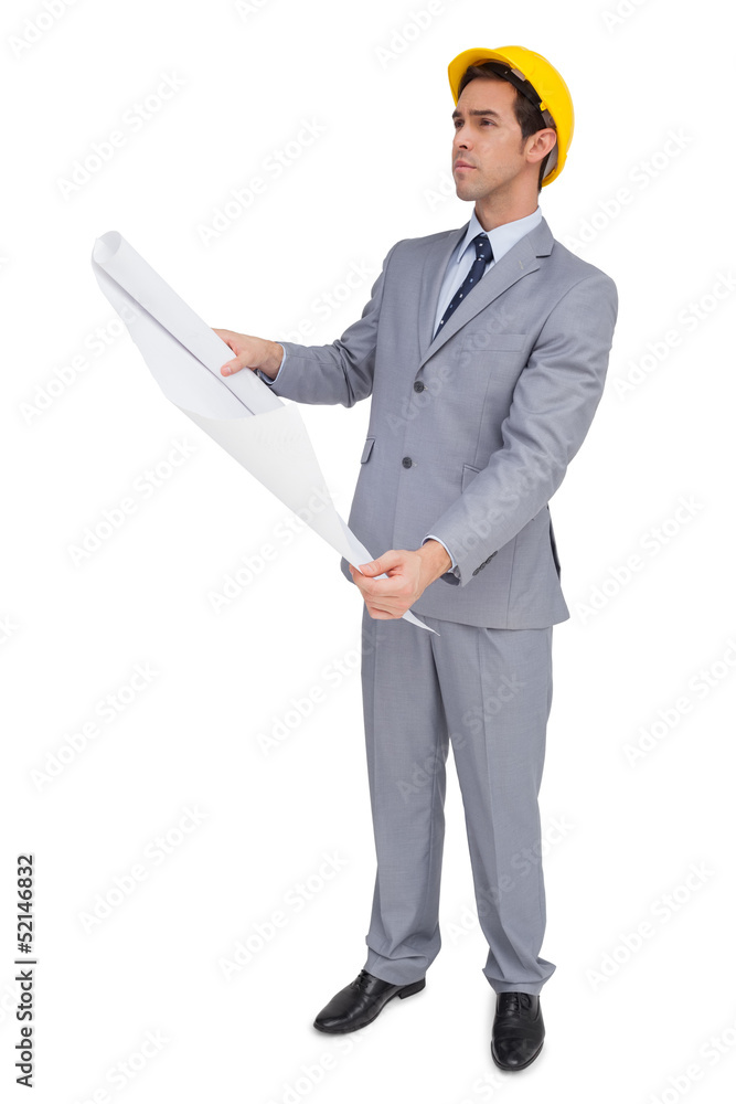 Serious architect with hard hat looking at plans thinking hard Serious architect with hard hat looking at plans thinking hard