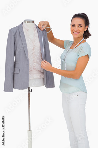 Fashion designer measuring blazer lapel on mannequin and smiling