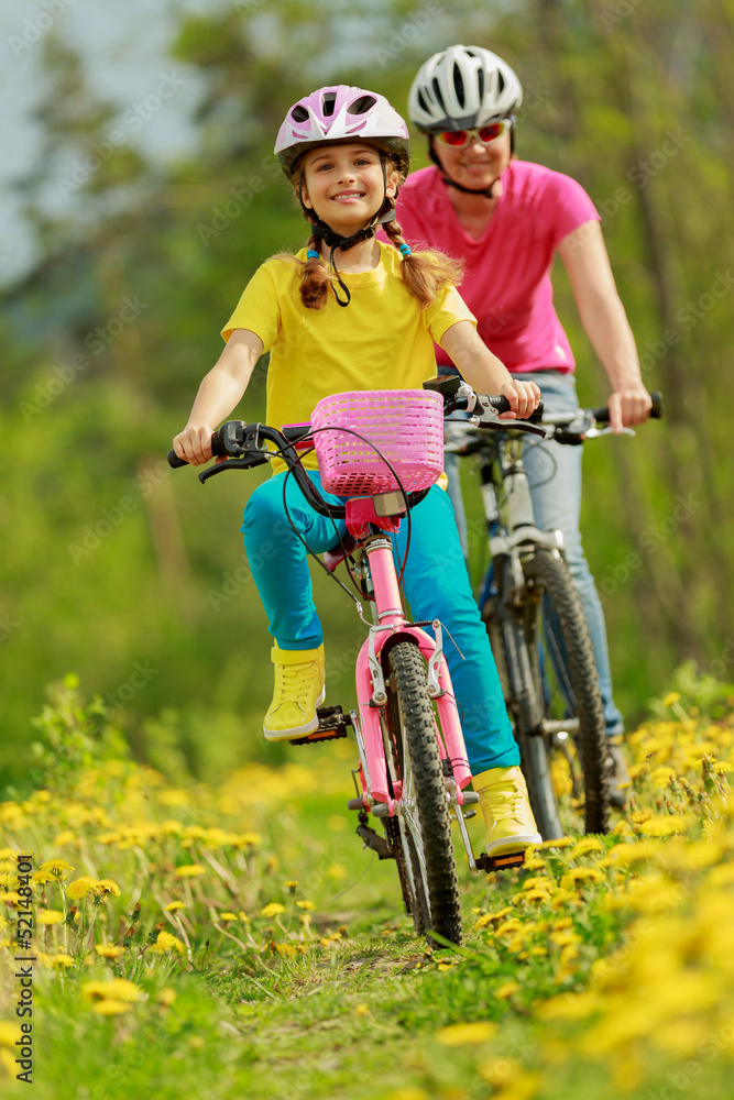 Obraz premium Bike riding - girl with mother on bike, active family concept