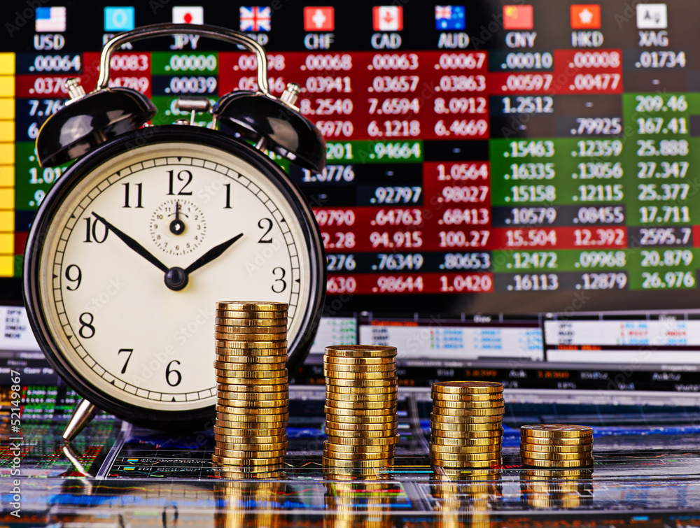 A downtrend columns of golden coins with an alarm clock. Financi A downtrend columns of golden coins with an alarm clock. Financi