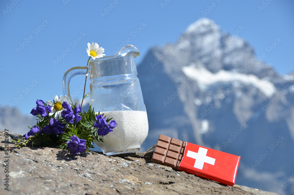 Swiss chocolate and jug of milk against mountain peak. Switzerla