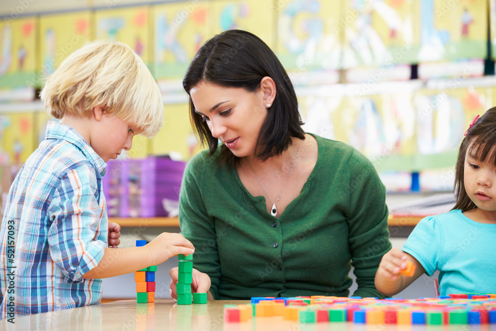 Fototapeta premium Elementary Pupils Counting With Teacher In Classroom
