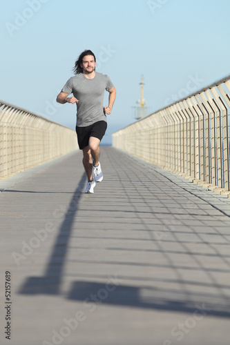 Front view of a sportsman running on a bridge