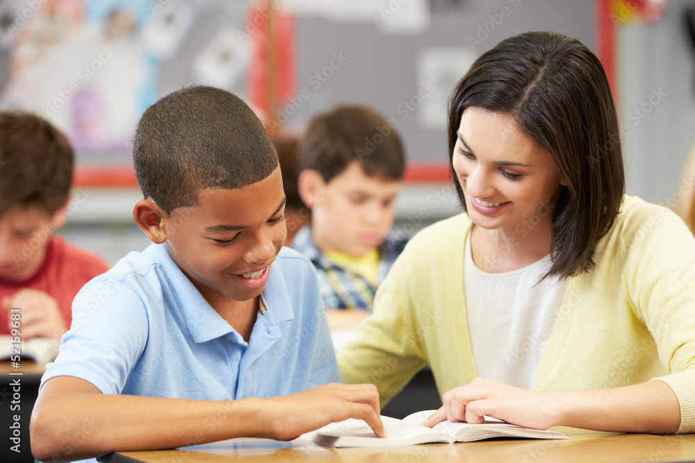 Teacher Reading With Male Pupil In Class Teacher Reading With Male Pupil In Class