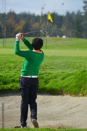 Golfer chipping the ball from sand trap