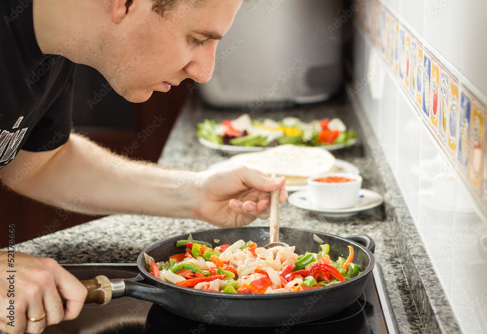 Man cooking vegetables and chicken in a pan