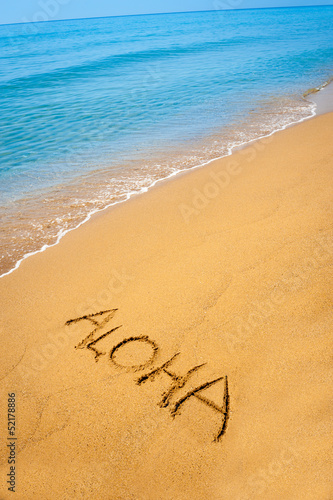Word Aloha written in sandy on tropical beach