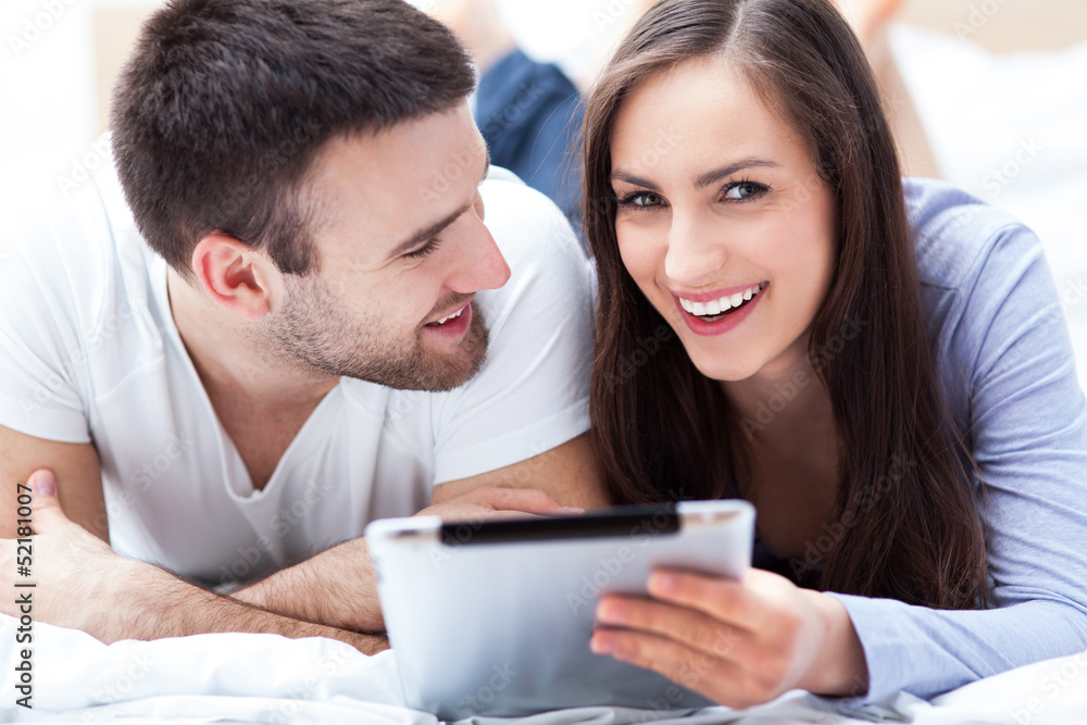 Couple with digital tablet lying on bed Couple with digital tablet lying on bed