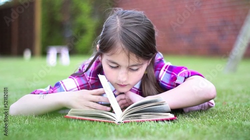 Little girl reading a book in summer on grass.Girl  Reading
