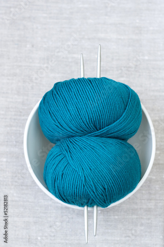 Two bright turquoise skeins of thread and needles for knitting photo