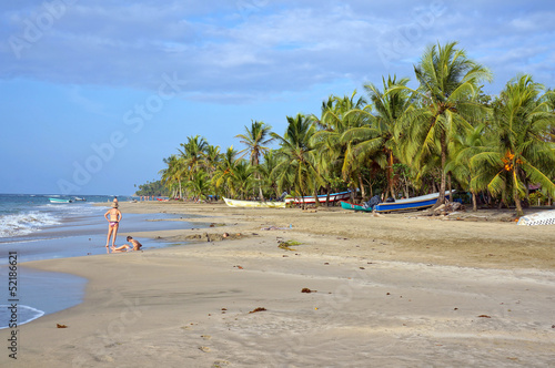 Caribbean beach with few tourists and fishing boats under coconut trees, Manzanillo, Costa Rica, Central America