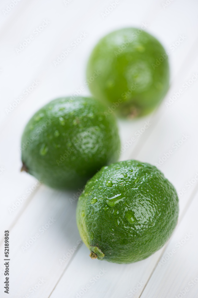 Vertical shot of three fresh lime fruits on wooden boards Vertical shot of three fresh lime fruits on wooden boards