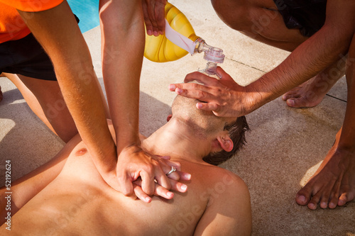 CPR, Man receiving cardiopulmonary resuscitation close to a swimming pool. photo