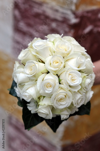 A bride holds her bouquet of white roses