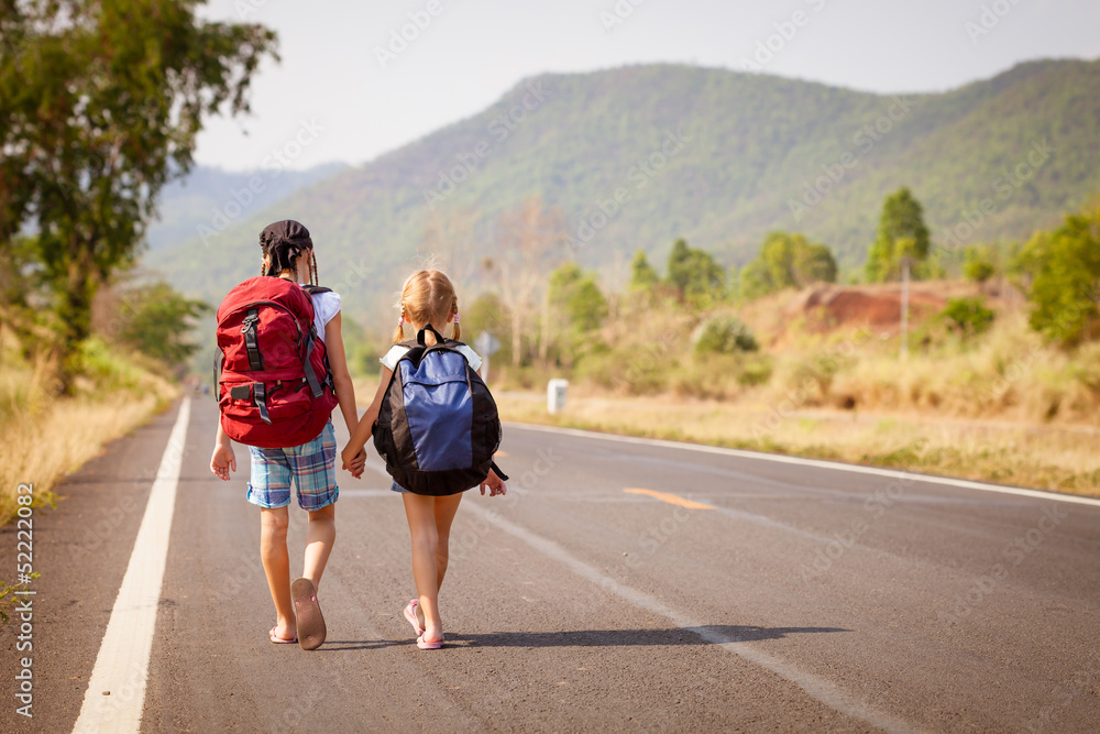 Fototapeta premium two little girls with backpack walking on the road