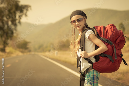 little girl with backpack walking on the road